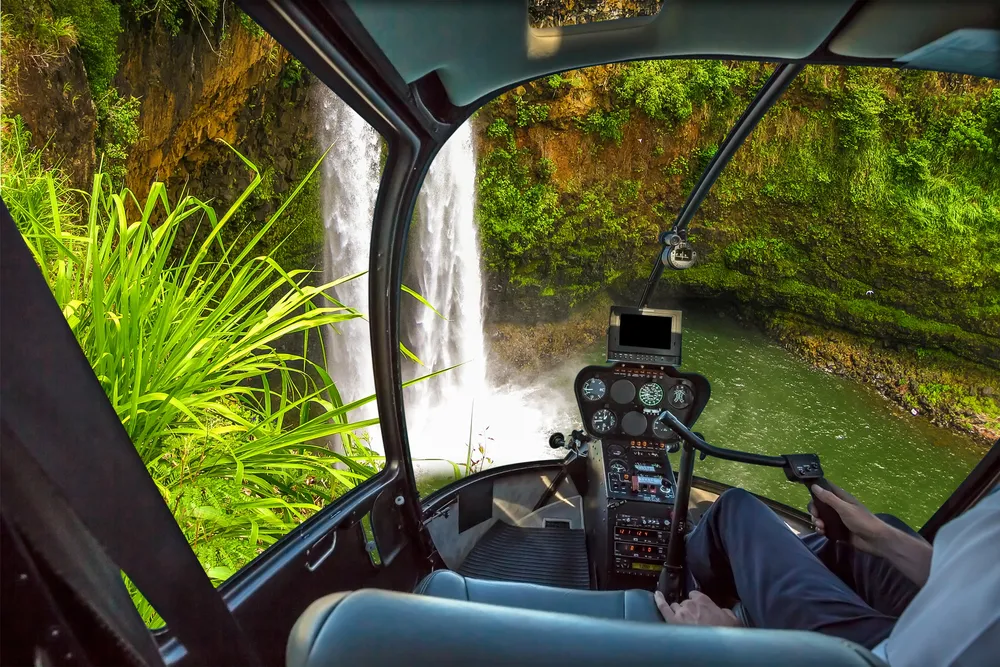 Helicopter flying over Kauai waterfalls and lush rainforest