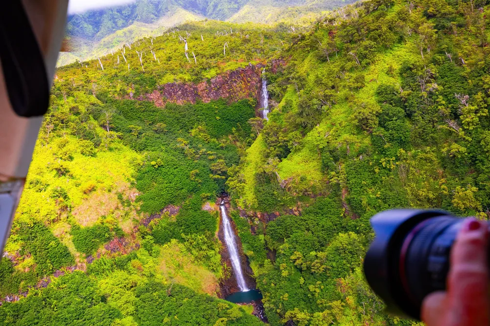 Passenger enjoying a helicopter tour over Maui with volcanic scenery below